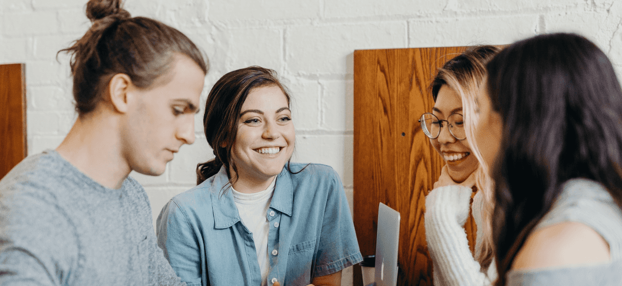 Um homem e três mulheres sorrindo durante uma reunião