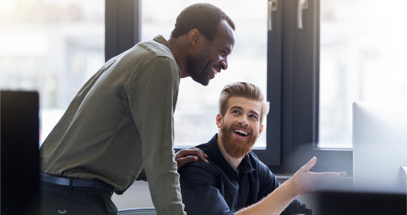 Two men smiling while looking at a monitor